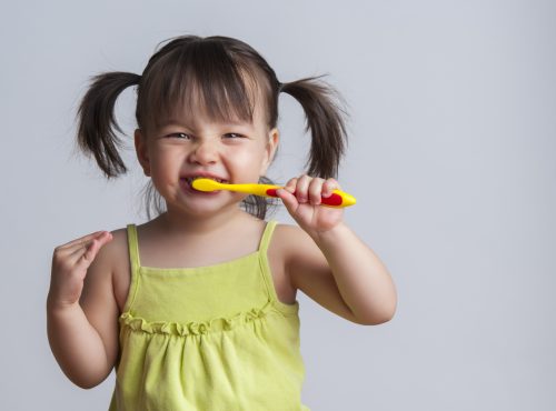 Toddler smiling while brushing her teeth